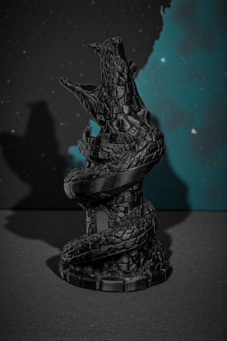 May include: A black, 3D-printed sculpture of a tower entwined by a serpent. The serpent's head is open, as if roaring. The tower has a small door and is textured to resemble stone. The background is a dark blue with a few white dots.