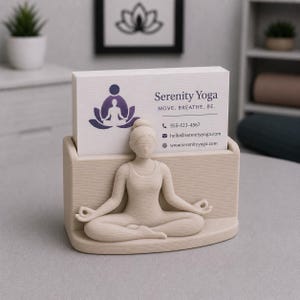 May include: A beige yoga-themed business card holder featuring a seated figure in a meditative pose. The holder displays business cards with the text "Serenity Yoga" and contact information. The design includes a lotus flower and a person in a yoga pose.