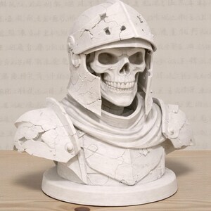 May include: A white bust of a skull wearing a cracked, weathered helmet and armor. The sculpture is on a round base, with visible details of the skull's teeth and facial structure. The bust is set against a neutral background.