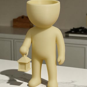 K&ouml;nnte beinhalten: Hellgelbe Figur in Form einer Person, die eine kleine Laterne h&auml;lt. Die Figur hat einen gro&szlig;en, offenen Kopf, und die Laterne ist quadratisch mit einem spitzen Dach. Die Figur steht aufrecht.