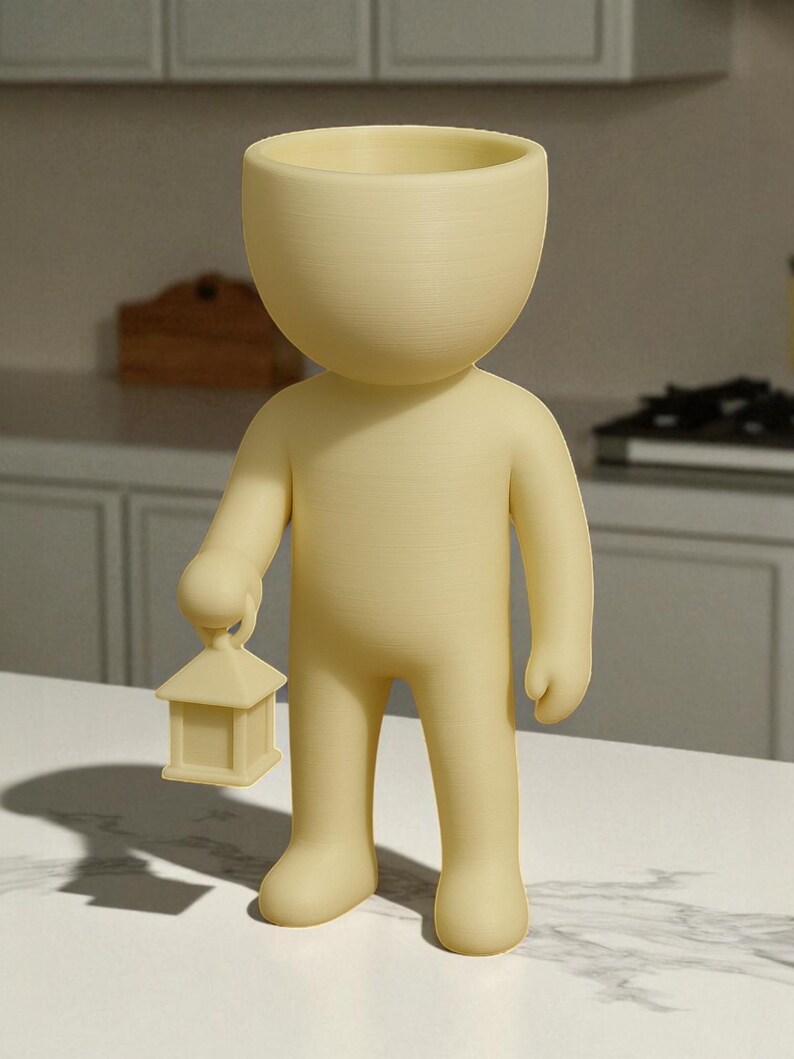 K&ouml;nnte beinhalten: Hellgelbe Figur in Form einer Person, die eine kleine Laterne h&auml;lt. Die Figur hat einen gro&szlig;en, offenen Kopf, und die Laterne ist quadratisch mit einem spitzen Dach. Die Figur steht aufrecht.