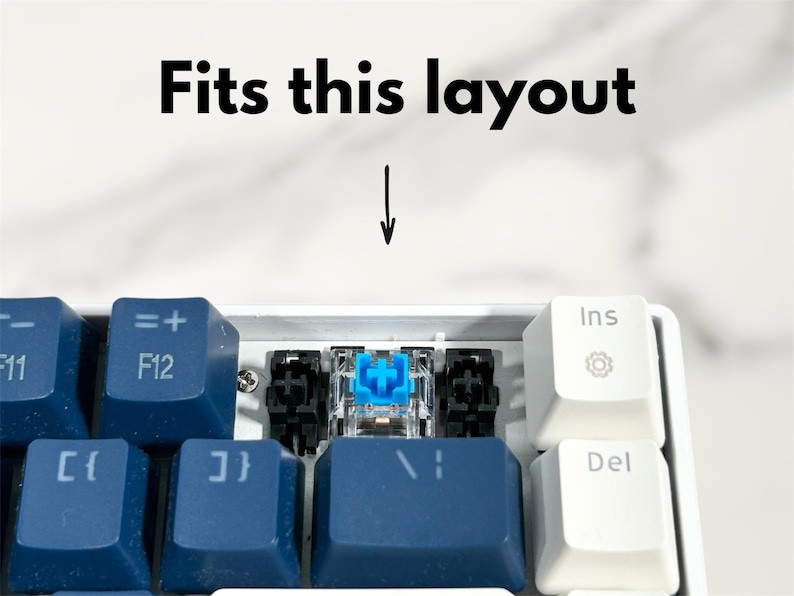 May include: A close-up of a blue and white keyboard with a single blue keycap. The keycap is labeled with a plus sign and is surrounded by black stabilizers.