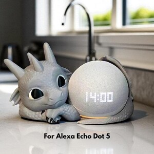 May include: A gray dragon-shaped speaker holder cradling a white smart speaker displaying the time 14:00. The holder is designed for an Alexa Echo Dot 5. The overall design is whimsical and decorative.