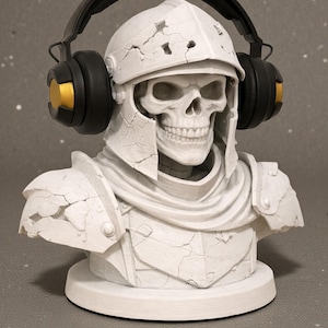 May include: A white bust of a skull wearing a cracked helmet and armor, with black and gold headphones. The bust is on a white circular base, with a gray background.