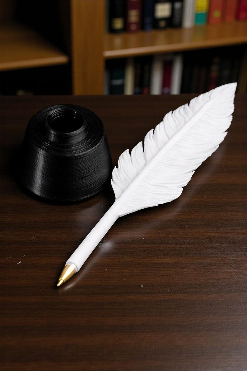 May include: A white feather pen with a gold-colored tip rests on a dark wooden surface next to a black inkwell. The pen is designed to resemble a feather, with detailed feathering. The inkwell is a cylindrical shape.