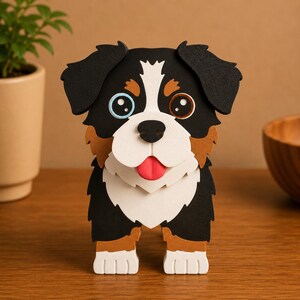 May include: A handcrafted, three-dimensional dog figurine. The dog has black, white, and brown fur, with one blue and one brown eye. Its tongue is red, and it stands on four white paws. The figurine is made of layered materials and is displayed on a wooden surface.