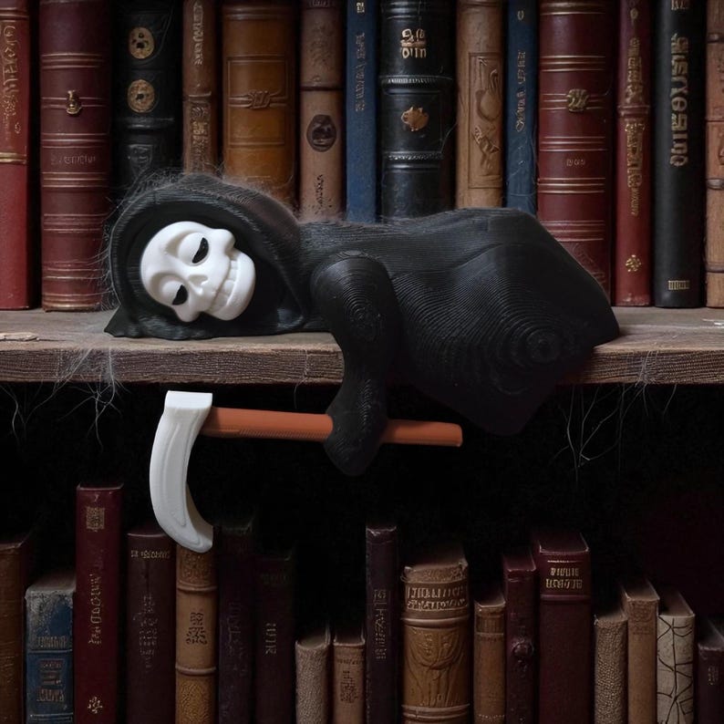 May include: A black Grim Reaper figurine with a white skull face and a black hooded robe, resting on a wooden shelf. The figurine holds a white scythe with a brown handle. The background features a collection of antique books.