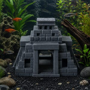 Puede incluir: Decoraci&oacute;n de acuario con forma de templo maya gris. La estructura presenta un dise&ntilde;o escalonado con aberturas rectangulares y un techo plano. La imagen muestra el templo sumergido en un acuario con peces vivos y plantas acu&aacute;ticas.