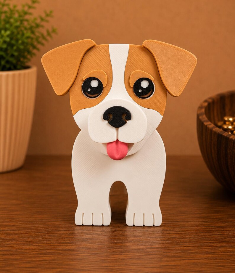 May include: A 3D-printed dog figurine with a white body, brown ears, and a brown patch on its head. The dog has large black eyes, a black nose, and a pink tongue. The figurine is standing on a wooden surface.