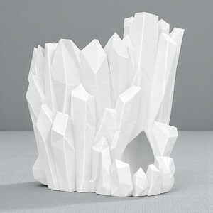 May include: A white, geometric crystal-shaped decorative object. The object has a hollow center and is composed of numerous angular, pointed shapes, resembling a cluster of crystals. The design is modern and minimalist, with a clean, monochromatic aesthetic.