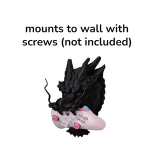 May include: A black dragon-shaped wall mount holding a white and pink Xbox controller. The controller has pink buttons and a blue accent. The text "mounts to wall with screws (not included)" is above the mount.