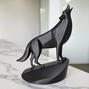 May include: A black 3D-printed sculpture of a howling wolf. The wolf is standing on a small, angled base. The sculpture has a geometric design and is displayed on a white marble surface.
