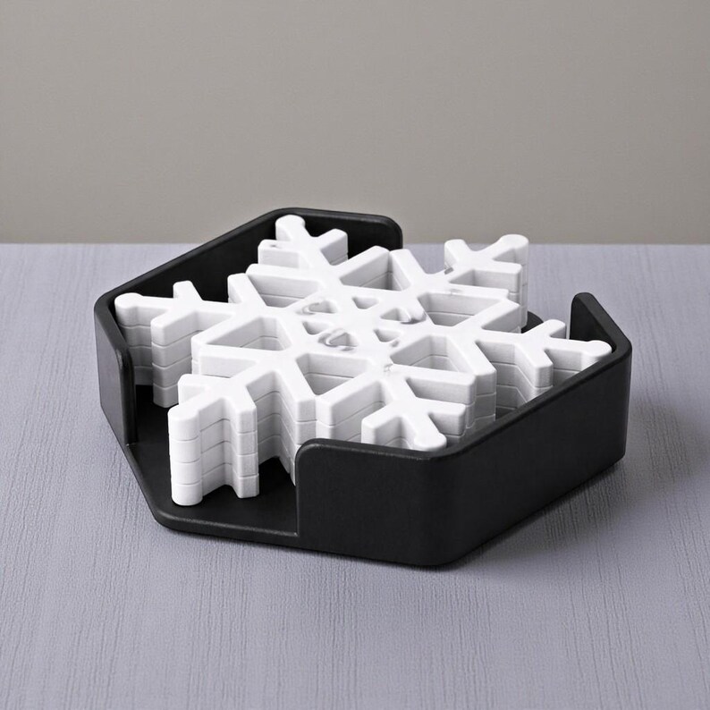 Puede incluir: Un juego de posavasos blancos con forma de copo de nieve en un soporte hexagonal negro. Los posavasos est&aacute;n apilados y listos para usar. El soporte tiene un dise&ntilde;o sencillo y moderno, ideal para bebidas.