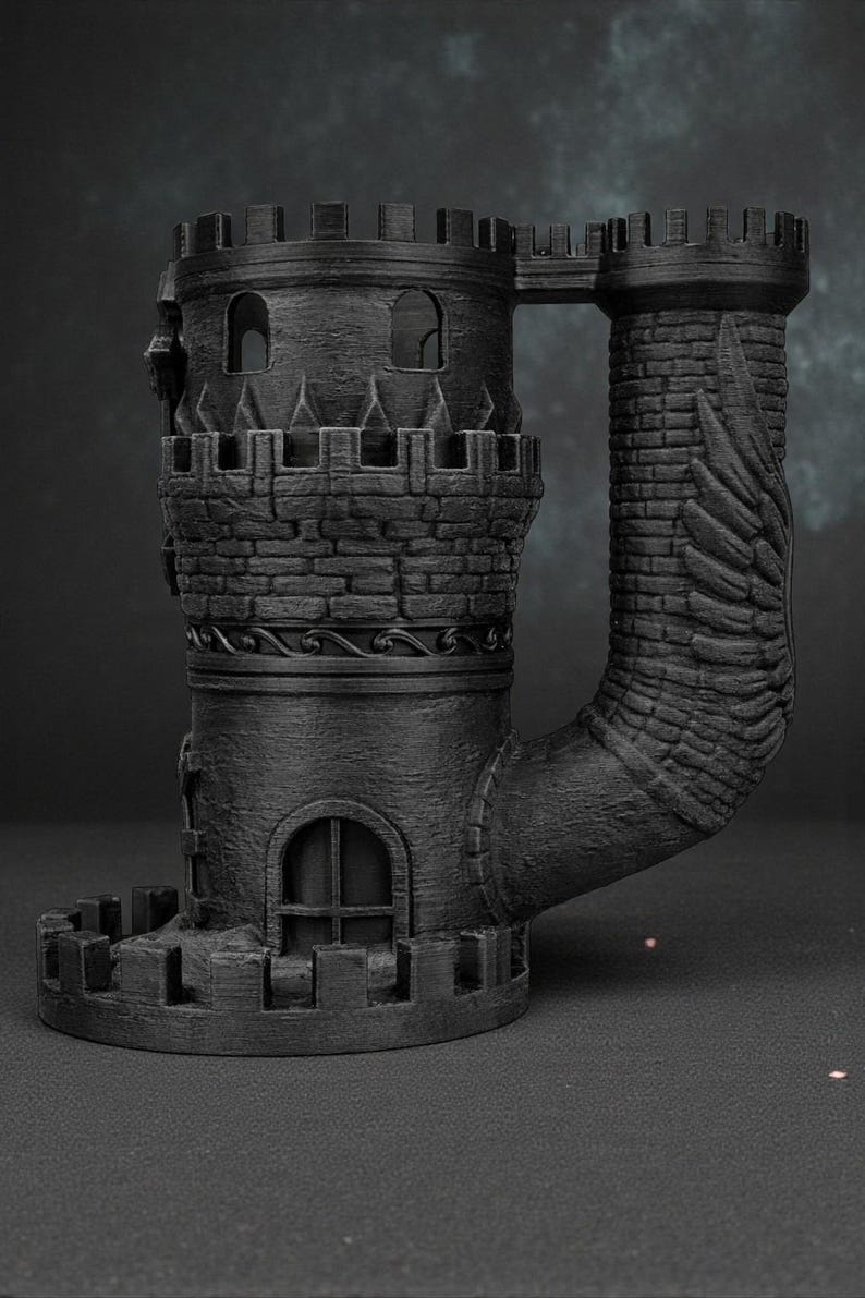 May include: A black, 3D-printed castle-shaped mug. The mug features two towers connected by a bridge, with detailed brickwork, arched windows, and crenelated battlements. The handle is a curved tower with a wing design.