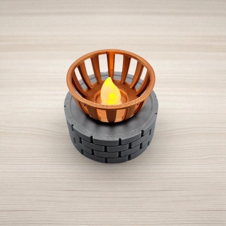 May include: A decorative candle holder with a copper-colored, slotted basket design. It sits atop a gray, brick-patterned base. The candle inside has a yellow, flickering flame, creating a warm ambiance. The candle holder is a unique home decor item.