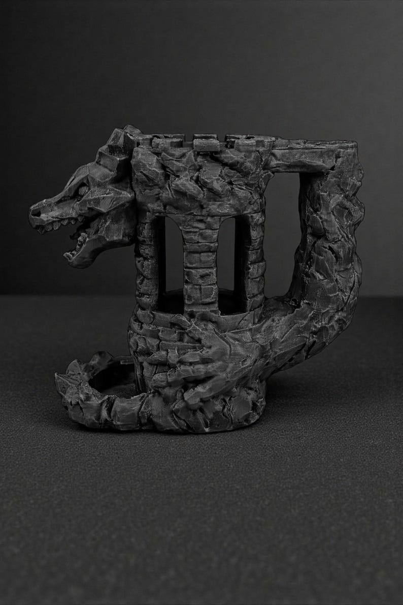 May include: A dark gray, fantasy-themed sculpture of a dragon-shaped castle. The castle features a dragon's head, a tower with arched windows, and a textured, stone-like appearance. The sculpture is designed for tabletop gaming.