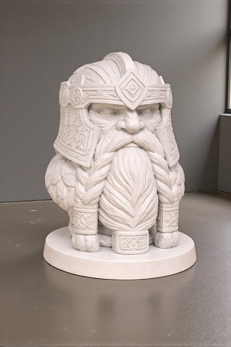 May include: A white sculpture of a dwarf's head and upper body, featuring a long, braided beard and a detailed helmet. The statue is on a circular base and has a stern expression. The dwarf is a decorative item.