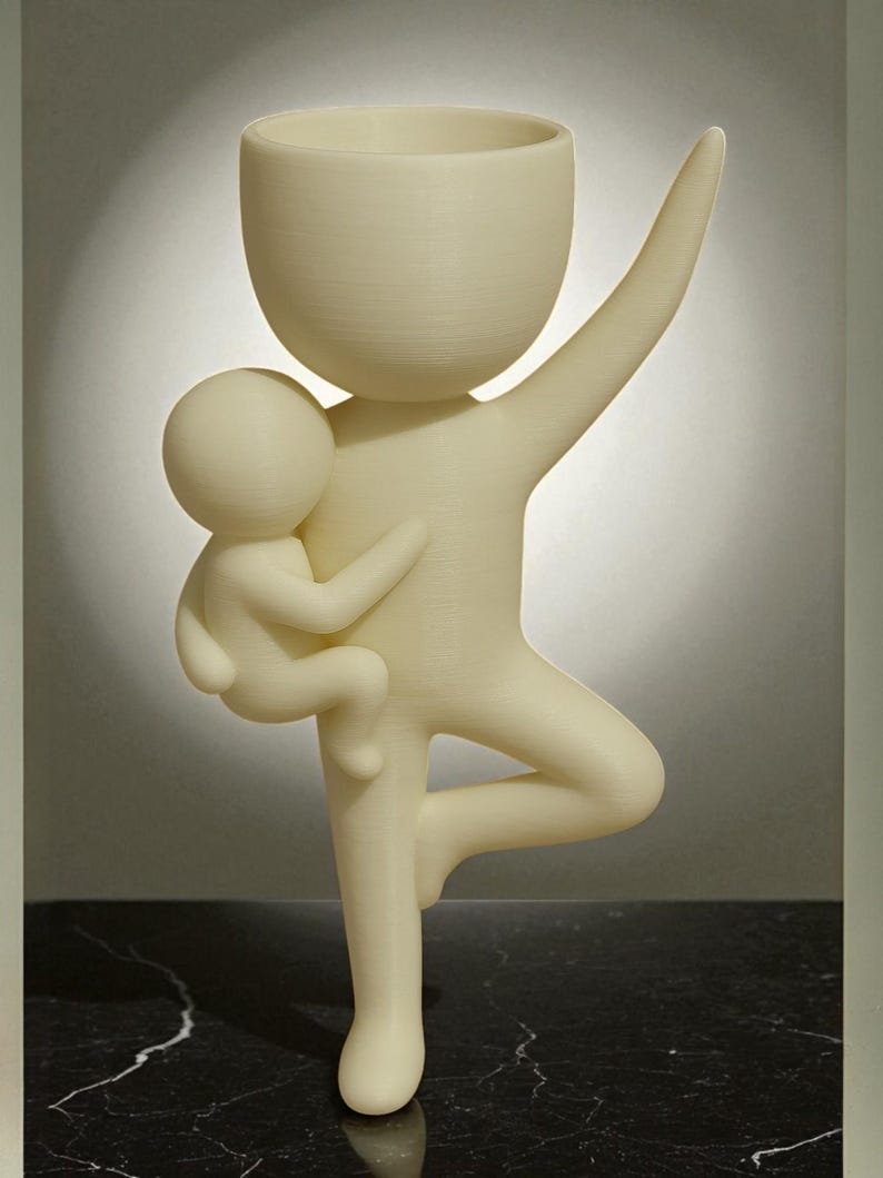 May include: A cream-colored sculpture of a figure holding a smaller figure, with one arm raised. The larger figure has a bowl-shaped head and is balancing on one leg. The sculpture is made of a textured material.