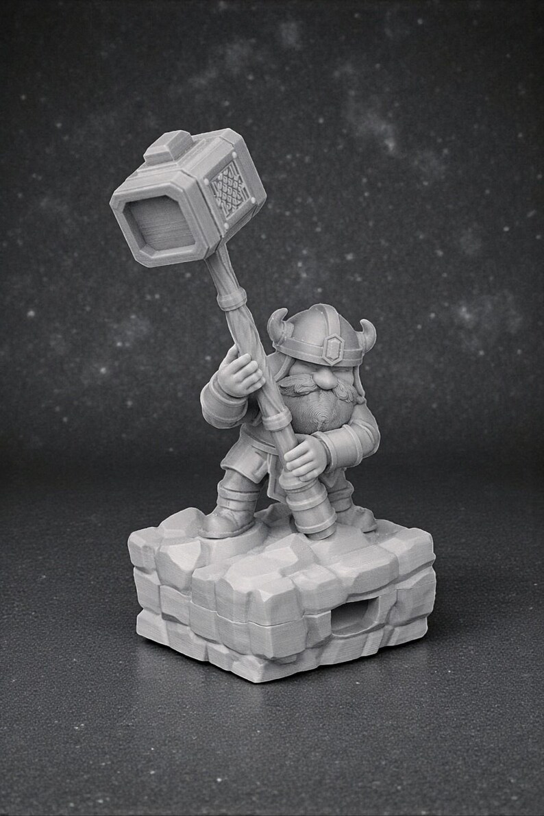 May include: A grey figurine of a dwarf, holding a large hammer aloft. The dwarf is wearing a helmet with horns and is standing on a rocky base. The hammer head has a decorative pattern. The figurine is a fantasy-themed collectible.