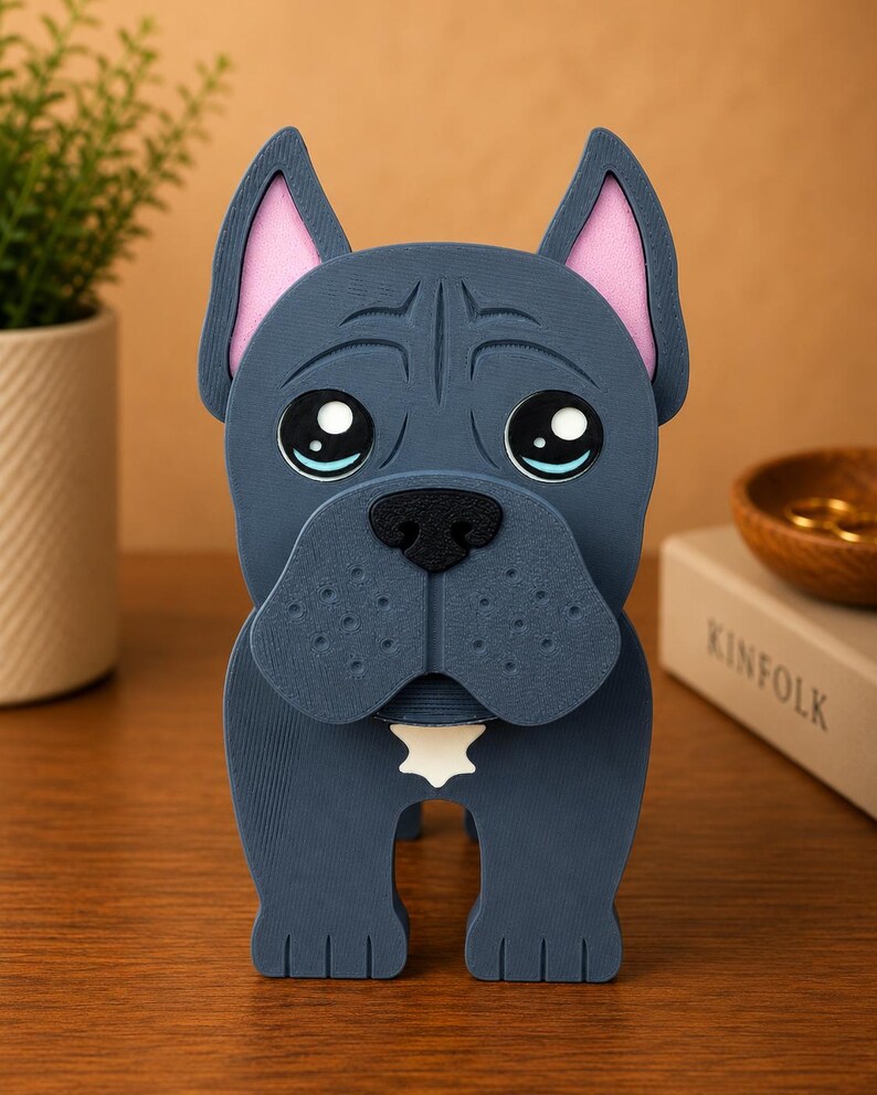 May include: A blue dog figurine with pink inner ears and a white star-shaped detail on its chest. The dog has large, expressive eyes and a black nose. The figurine is made of a solid material and stands upright.
