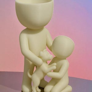 May include: A cream-colored figurine depicts a family with a dog. The adult figure holds the dog, while a child kneels to interact with it. The figures have rounded heads and smooth bodies. The background is a gradient of pink and purple.