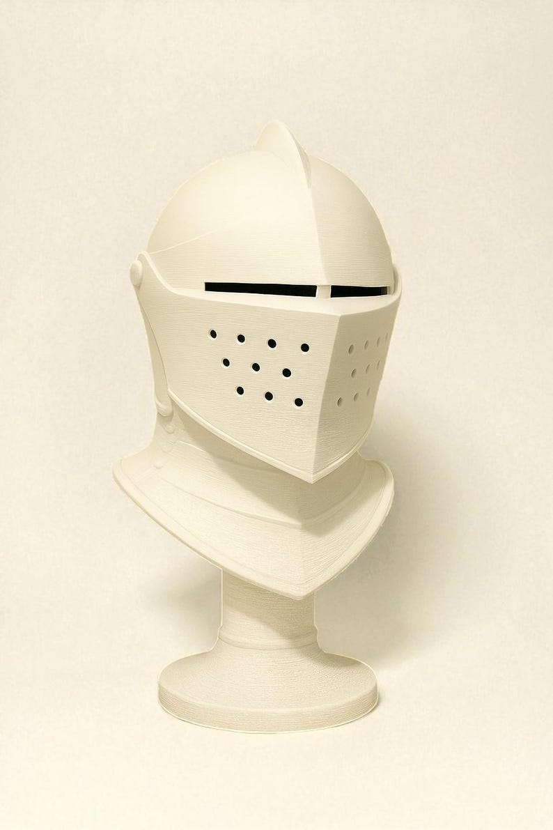 May include: A cream-colored knight's helmet with a visor featuring small circular holes. The helmet is mounted on a pedestal, showcasing the neck guard and the overall shape of the medieval headgear. The design is simple and elegant.