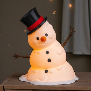 May include: A novelty snowman lamp, featuring a black top hat with a red band. The snowman has a carrot nose, black button eyes, and twig arms. The lamp gives off a warm light, ideal for festive decorations.