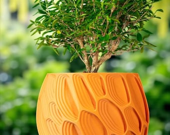 May include: A decorative orange plant pot with a textured design, holding a small bonsai tree. The bonsai has small green leaves and a brown trunk. The pot's design features layered, curved shapes. The background is a blurred green.