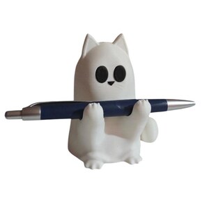 May include: A white cat-shaped pen holder with black eyes and a small black nose. The cat is holding a blue pen with a silver tip. The pen holder is a cute and functional desk accessory.