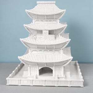 May include: A white, multi-tiered pagoda model with a detailed roof design. The model features the Japanese text "ホテル" (hoteru, hotel) and is set against a light blue background. The architectural model is a decorative item.
