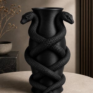 May include: Black vase with two snakes coiled around the body. The snakes' heads are at the top, and their bodies intertwine. The vase has a textured surface and sits on a neutral-colored table. Decorative home decor.