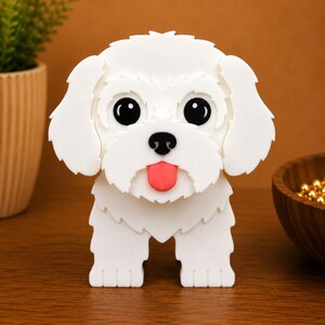 May include: A white, three-dimensional dog figurine with large black eyes, a pink tongue, and a black nose. The dog has fluffy-looking fur and is standing on a wooden surface. The background is a warm brown color.