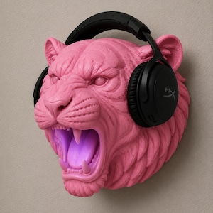 May include: A pink, sculpted tiger head with an open mouth and black headphones. The tiger's mouth glows with a purple light. The headphones have the HyperX logo.