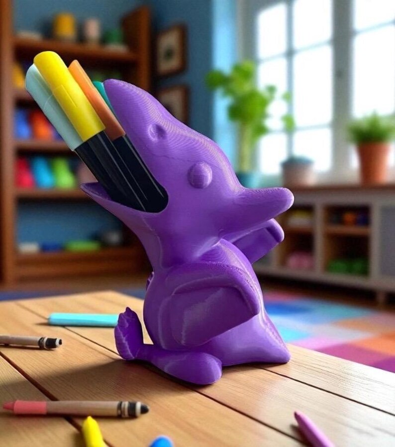 May include: A purple dolphin-shaped desk organizer holding colorful markers. The organizer is made of a solid material and sits on a wooden table with scattered pencils and crayons. The background includes a bookshelf and a window.