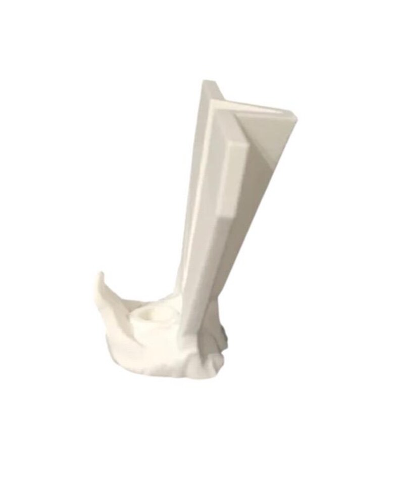 May include: A white, abstract sculpture with a folded, layered design. The sculpture has a curved base and a series of upright, angled panels. The overall form is smooth and modern, with a minimalist aesthetic.