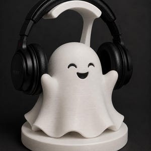 May include: A white 3D-printed headphone stand shaped like a smiling ghost, holding black headphones. The stand has a round base and a curved top to hold the headphones. The headphones are black with the brand name "SONY" visible.