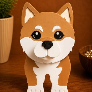 May include: A 3D-printed Shiba Inu dog figurine. The dog has a brown and white coat, with large black eyes and a black nose. The figurine is standing upright on a wooden surface. The ears are pointed and the tail is not visible.
