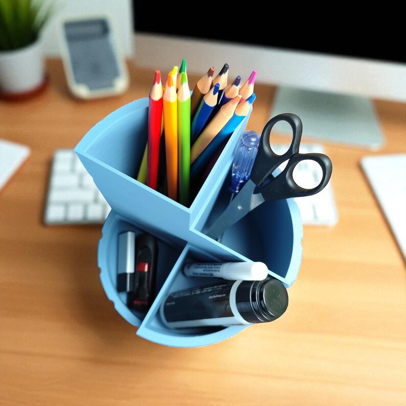 Op de afbeelding: Een lichtblauwe bureau-organizer gevuld met kleurpotloden, een zwarte schaar, een pen en diverse kantoorbenodigdheden. De organizer is verdeeld in meerdere compartimenten.