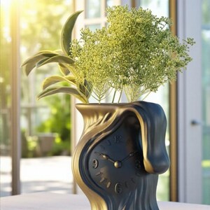 May include: A black and gold-colored decorative vase with a clock face design, holding green plants. The vase has a unique, melting appearance. The clock shows the time as approximately 10:10.