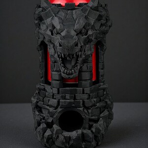 May include: A black, 3D-printed can cooler shaped like a castle with a snarling wolf's head. The cooler has a red interior, and a red can is visible inside. The design features a stone-like texture.