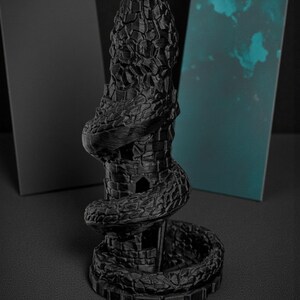 May include: A black, 3D-printed sculpture of a tower entwined by a snake. The tower has a textured, stone-like appearance with a spiraling snake wrapped around it. The sculpture is set against a dark background.