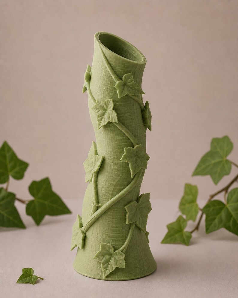 May include: A green vase with a textured surface and a curved shape. The vase is adorned with ivy vines and leaves. The vase is approximately 10 inches tall.