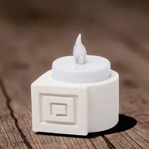May include: A white LED candle with a realistic flickering flame. The candle sits atop a square base with a recessed geometric design. The candle is designed to look like a real candle.