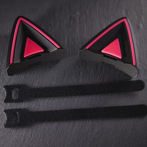 May include: Two black cat ear headphones with pink accents and two black velcro straps.