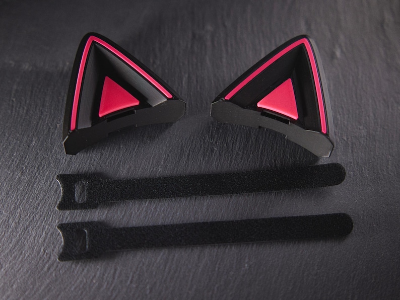 May include: Two black cat ear headphones with pink accents and two black velcro straps.