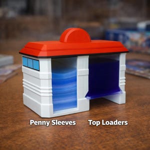 Puede incluir: Un contenedor de almacenamiento de tarjetas blanco y rojo con detalles azules. El contenedor tiene dos compartimentos abiertos, uno lleno de tarjetas azules. El texto en la base dice "Penny Sleeves" y "Top Loaders".