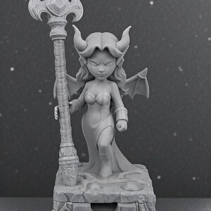 May include: A gray figurine of a female demon with horns, wings, and a staff. The figure is standing on a stone base. The staff has a decorative top with a gem. The demon is wearing a dress and boots.