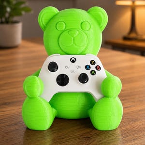 May include: A bright green 3D-printed bear figure holding a white Xbox controller. The controller has black buttons and colored action buttons. The bear has a friendly, cartoonish design.
