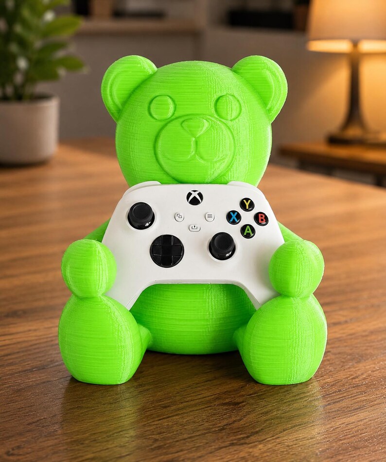 May include: A bright green 3D-printed bear figure holding a white Xbox controller. The controller has black buttons and colored action buttons. The bear has a friendly, cartoonish design.