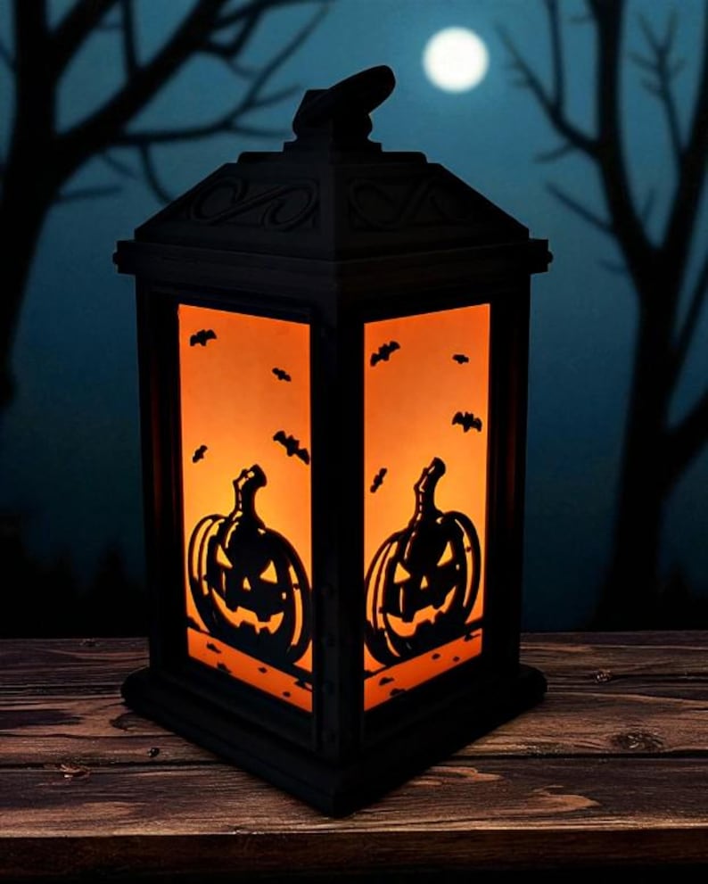 May include: Black Halloween lantern with orange interior, featuring jack-o'-lantern and bat silhouettes. The lantern is set against a backdrop of a moonlit night with silhouetted trees, creating a spooky ambiance. Perfect for Halloween decor.